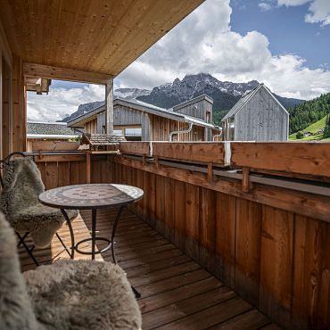 Ein Balkon mit Holzmöbeln und einem atemberaubenden Bergblick